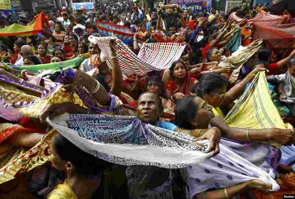Hindu devotees hold up scarves to receive rice as offerings being distributed by the temple authority on the occasion of the Annakut festival in Kolkata, India.