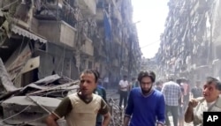 In this image made from video and posted online from Validated UGC, men look at damaged buildings after airstrikes hit Aleppo, Syria, April 28, 2016.