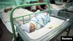 FILE - A newborn rests near his mother at a hospital in Camaguey, Cuba, June 19, 2015. It was in that month that the World Health Organization declared Cuba the first country in the world to eliminate the transmission of HIV and syphilis from mother to child. 