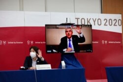 Presiden Komite Olimpiade Internasional (IOC) Thomas Bach (di layar) dan Presiden Olimpiade Tokyo 2020, Seiko Hashimoto, (kiri) pada pertemuan virtual penyelenggaraan Olimpiade di Tokyo, 8 Juli 2021. (Foto: Behrouz Mehri/AP)