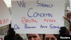 A member of the civil society hold placard and chant slogans to condemn the attack on the Army Public School by Pakistan Taliban gunmen, during a rally with others in Lahore, Dec. 18, 2014. 
