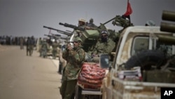 A Libyan rebel scans the field as they wait for the signal to advance at an intersection just outside Brega, April 3, 2011