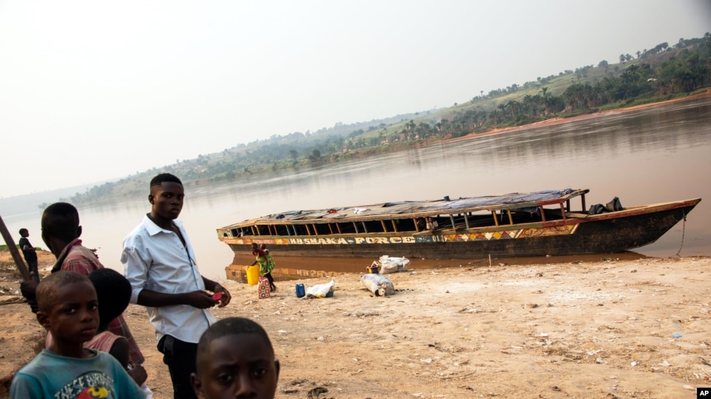 Quelques personnes à côté d'un bateau vide, sur le bord de la rivière Kasaï, au port de Tshikapa, en République démocratique du Congo, le 28 juillet 2017.