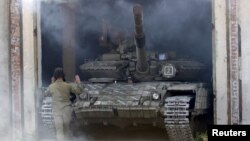 A member of the self-proclaimed Luhansk People's Republic (LNR) forces guides a tank to park after withdrawing it further from the frontline outside Luhansk, Ukraine, Oct. 3, 2015.