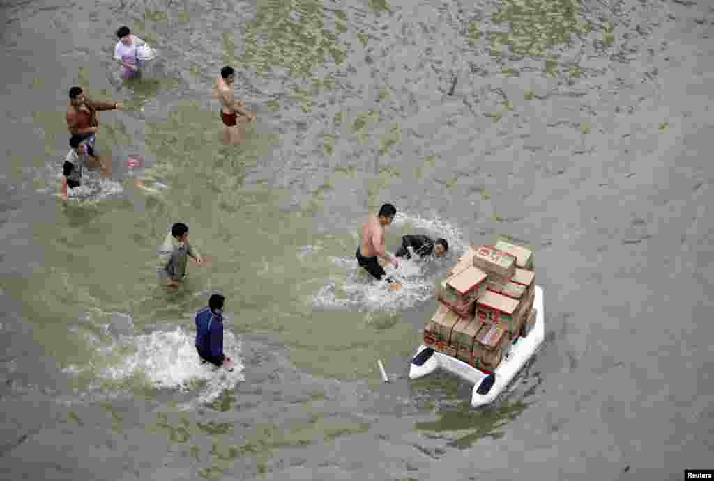 Môt người tình nguyện chở các thùng thực phẩm tiếp tế trên một xuồng cao su bị té xuống nước, trên đường phố bị lụt sau khi trận bão Fitow thổi vào thành phố Dư Diêu, Trung Quốc.