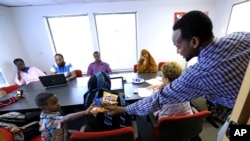 FILE - Somali immigrant leader Jamal Dar, right, who arrived in the U.S. two decades ago, hands out snacks to a boy at a community engagement and civic language class for former Somali residents at AYCO offices in East Portland, Ore., July 21, 2015.