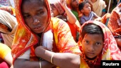 A garment worker who survived the Rana Plaza building collapse takes part in a protest with her child to demand compensation, at the factory site in Savar, Bangladesh, October 24, 2013.