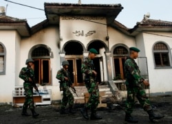 Tentara berjalan melewati masjid milik Ahmadiyah yang terbakar, di Ciampea, Jawa Barat, 2 Oktober 2010. (REUTERS/Dadang Tri)