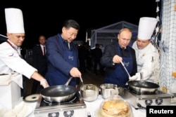 Presiden Rusia Vladimir Putin dan Presiden China Xi Jinping membuat pancake saat mengunjungi pameran Far East Street di sela-sela Forum Ekonomi Timur di Vladivostok, Rusia, 11 September 2018. (Foto: via Reuters)