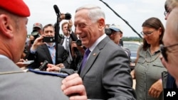 Defense Secretary Jim Mattis smiles at a member of the German army as he speaks with the media at the Pentagon, June 20, 2018, in Washington. 