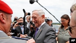 Defense Secretary Jim Mattis smiles at a member of the German army as he speaks with the media at the Pentagon, June 20, 2018, in Washington. 