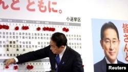 기시다 후미오 일본 총리가 31일 중의원 선거에서 당선된 자민당 후보들 이름 위에 꽃을 붙이고 있다.