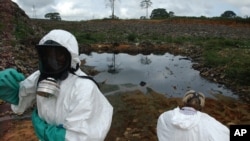FILE - Waste removal experts work to remove hazardous black sludge from a garbage dump in Abidjan, Ivory Coast, Sept. 17, 2006. Many victims have still not received compensation.