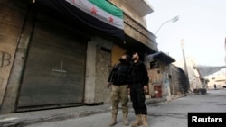FILE - Free Syrian Army fighters look at a Syrian opposition flag in Aleppo's Bustan al-Basha district.