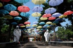 Para pekerja menyemprotkan cairan disinfektan untuk mencegah penularan virus corona (Covid-19) di Solo, Jawa Tengah, 18 Juni 2020. (Foto: Antara via Reuters)