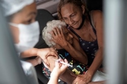 Seorang perempuan lansia disuntik vaksin CoronaVac dari Sinovac, China, di pusat vaksinasi drive-thru di Rio de Janeiro, Brazil, Senin, 1 Februari 2021.