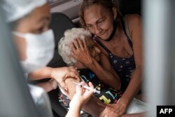 An elderly woman gets a shot of China's Sinovac CoronaVac vaccine as part of a priority COVID-19 vaccination program for the elderly at a drive-thru vaccination center in Rio de Janeiro, Brazil, Monday, Feb. 1, 2021.