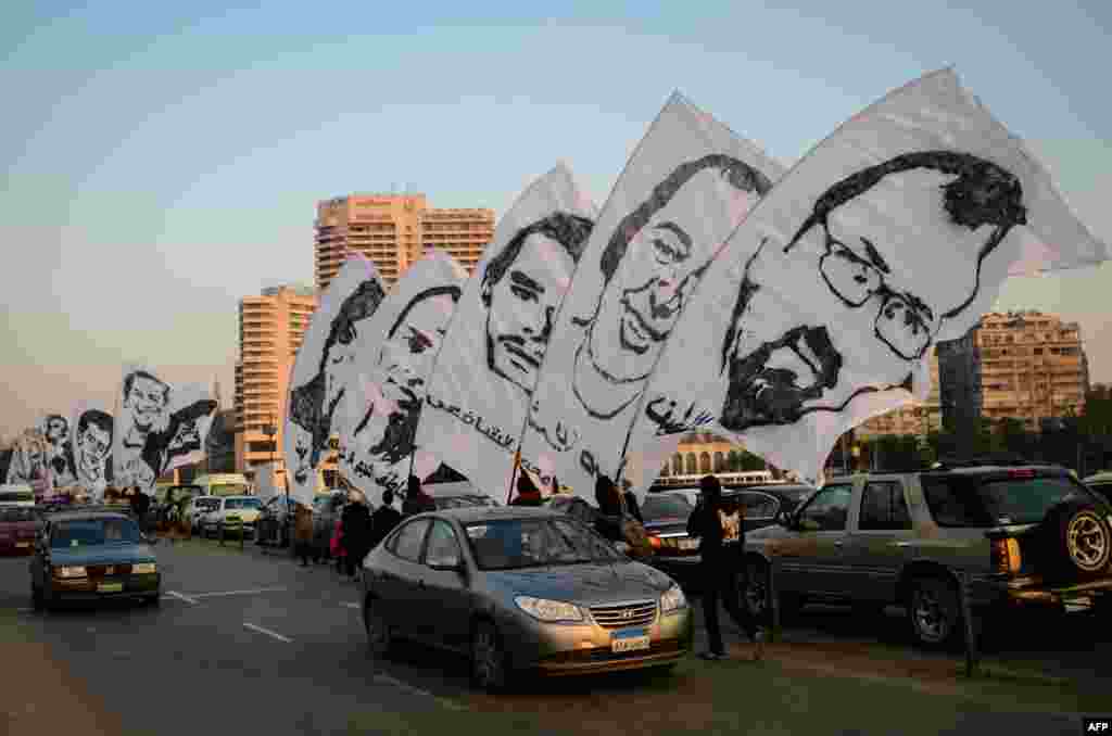 Demonstran Mesir melakukan unjuk rasa di Kairo dengan membawa gambar para korban yang tewas akibat kekerasan oleh pasukan anti huru-hara Mesir tahun lalu. 