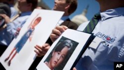 FILE - Fathers who lost their children to spousal abduction to Japan hold photos of their children during a news conference on Capitol Hill in Washington, May 5, 2010.