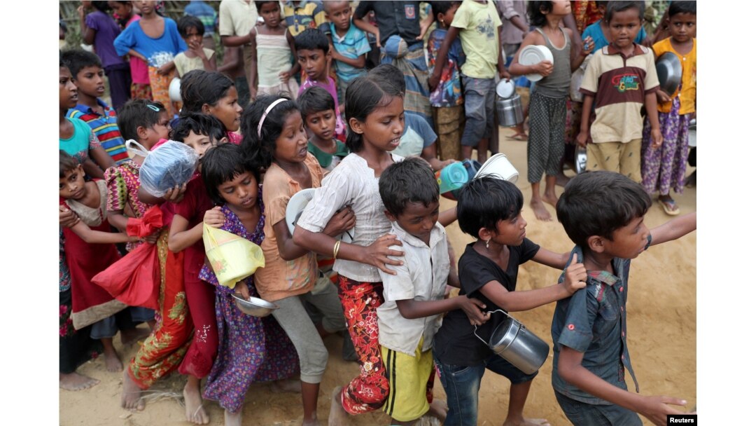 FILE - Rohingya refugee children push each other while waiting outside of an aid distribution center to receive aid supplies in the Palong Khali refugee camp in Cox's Bazar, Bangladesh, Nov. 15, 2017.