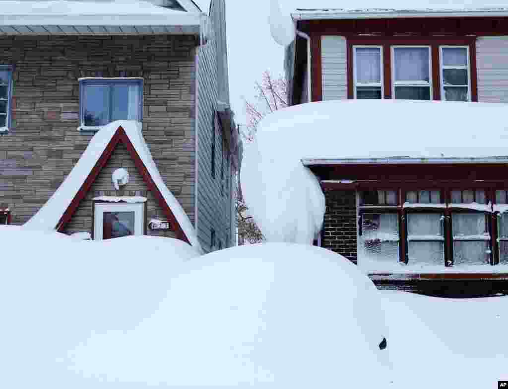 La neige presque a presqu&rsquo;entièrement couvert un véhicule et le toit des maisons dans la zone sud de Buffalo, jeudi 20 novembre 2014, à Buffalo, NY.