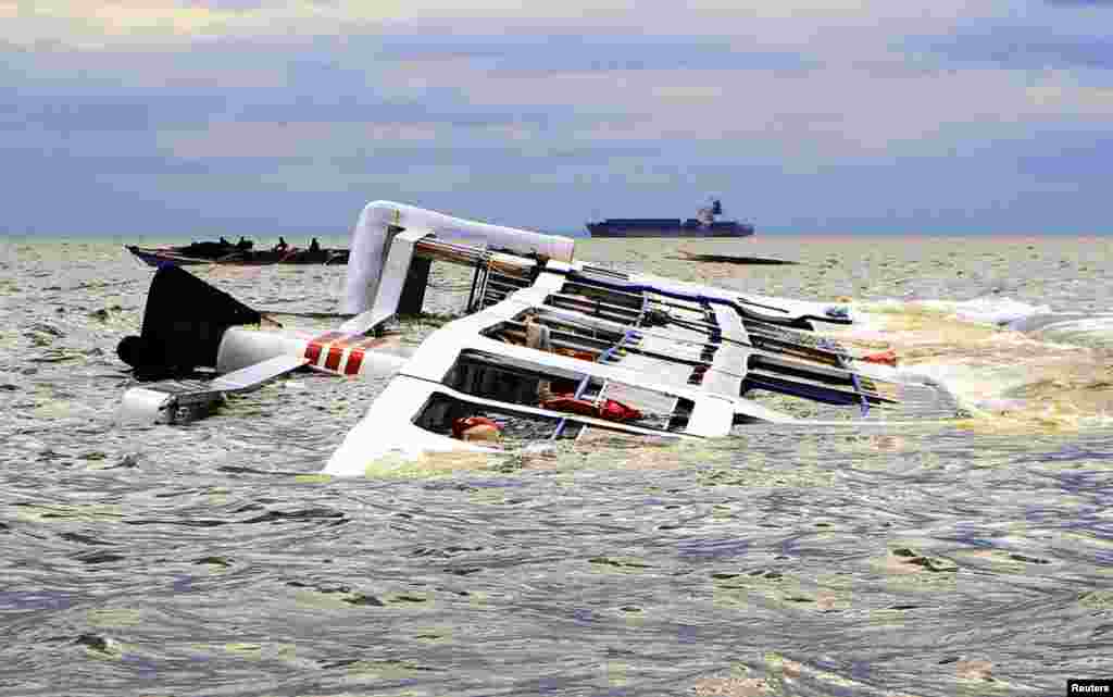 A fishing boat passes the Super Shuttlae Ferry 7 which capsized in strong winds and huge waves unleashed by Typhoon Kalmaegi, locally named Luis, in Manila Bay, Philippines. All 15 crew of the ferry were rescued.