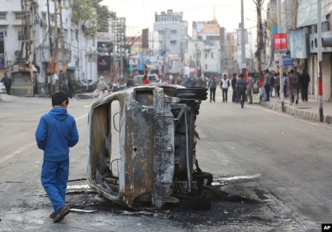 FILE - A boy walks past a vehicle burnt by a mob during a protest against Thursday's attack on a paramilitary convoy, in Jammu, India, Feb. 15, 2019.