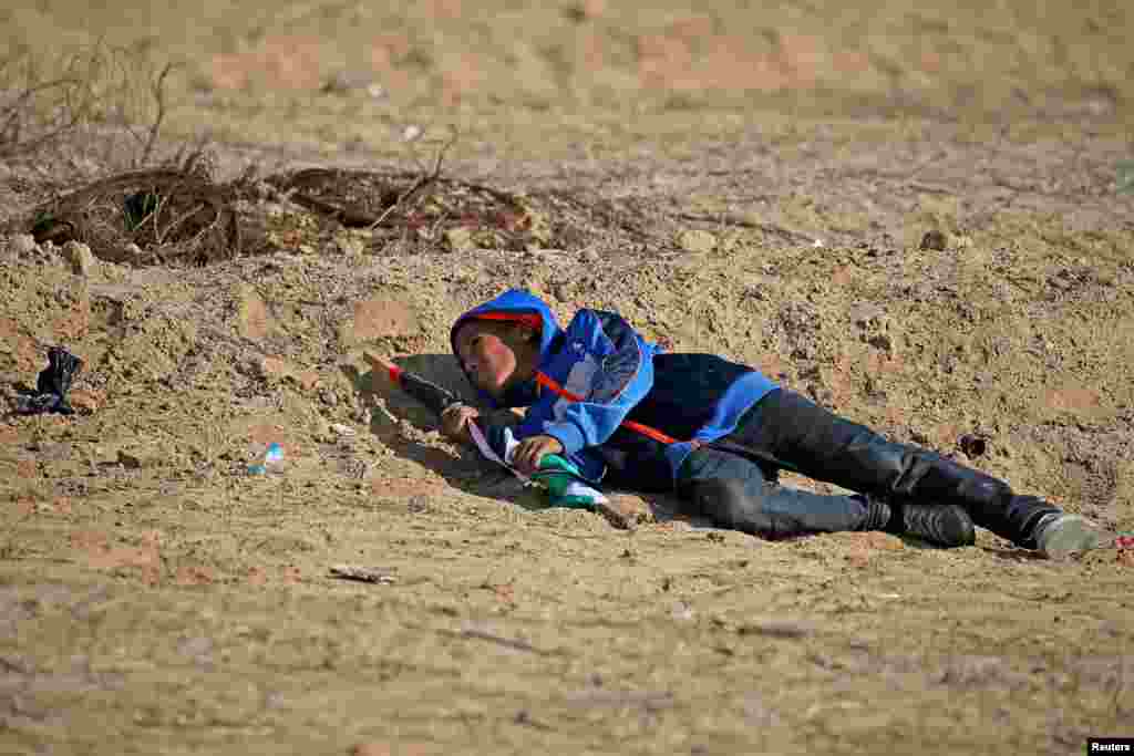 A Palestinian boy takes cover from Israeli fire during an anti-Israel protest at the Israel-Gaza border fence, in the southern Gaza Strip.