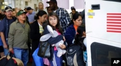 FILE - Immigrants from El Salvador and Guatemala, who entered the U.S. illegally, board a bus after they were released from a family detention center in San Antonio, Texas, July 7, 2015.