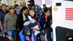 FILE - Immigrants from El Salvador and Guatemala, who entered the country illegally, board a bus after they were released from a family detention center in San Antonio, Texas, July 7, 2015.