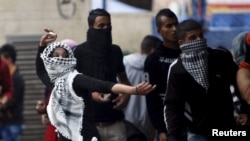 A Palestinian girl hurls stones at Israeli troops in the West Bank city of Hebron Oct. 7, 2015. A suspected Palestinian militant stabbed and wounded an Israeli soldier, snatched his gun and was shot dead by special forces, police said.