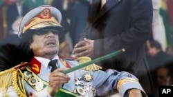 FILE - Libyan leader Moammar Gadhafi gestures with a green cane as he takes his seat behind bulletproof glass for a military parade in Green Square, Tripoli, Libya.