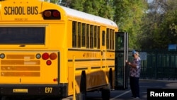 An employee waits to assist a student off a bus as in-person learning resumes with restrictions in place to prevent the spread of coronavirus disease (COVID-19) at Rover Elementary School in Tempe, Arizona, U.S., August 17, 2020. (REUTERS/Cheney Orr) 