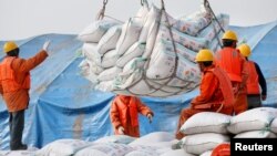 Workers transport imported soybean products at a port in Nantong, Jiangsu province, China March 22, 2018. China announced plans to increase taxes on $50 billion of U.S. goods, such as soybeans, airplanes and cars. (REUTERS/Stringer)