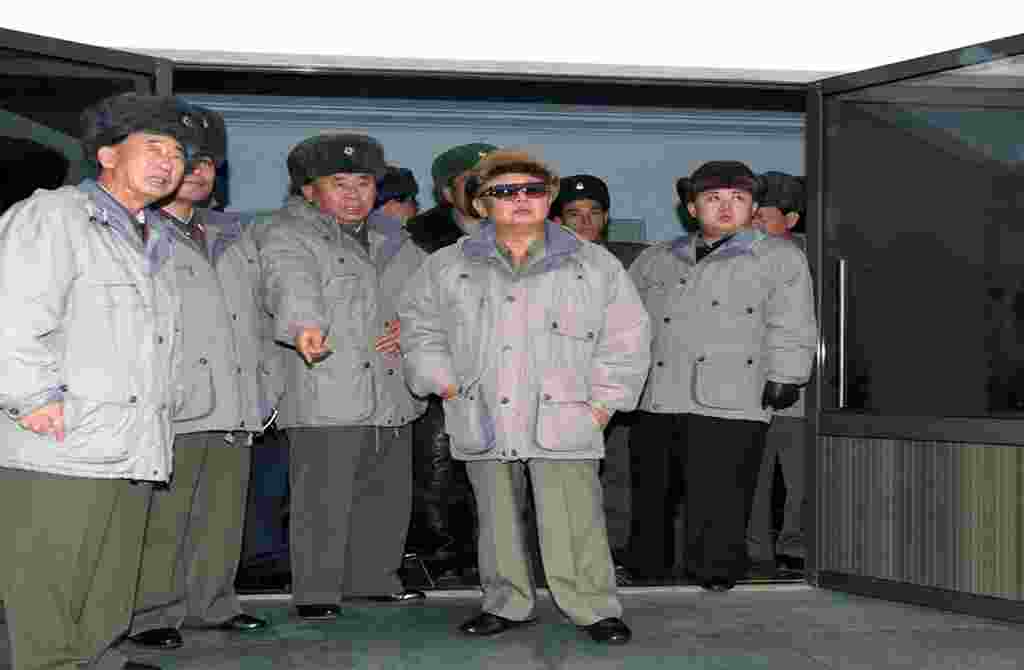 Dalam foto tanpa tanggal ini, terlihat Kim Jong Il (tengah) ditemani oleh putranya Kim Jong Un (kanan), mengunjungi Unit 1016 Angkatan Udara Korea Utara di sebuah lokasi yang tidak diketahui (foto: AFP).