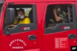 Chinese firefighters wear masks as they wait in their truck near the site of an explosion in northeastern China's Tianjin municipality, Aug. 15, 2015.
