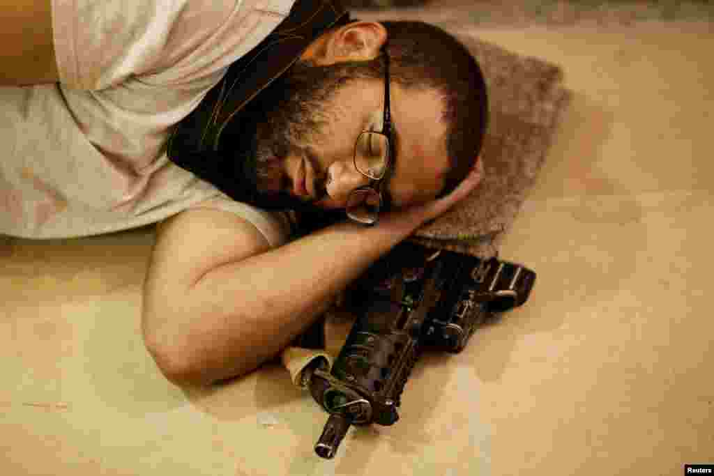 A Jewish worshipper sleeps next to his weapon near the Western Wall on Tisha B'Av, a day of fasting and lament, in Jerusalem's Old City.