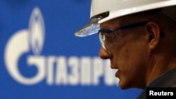 یکی از کارگران مشغول در پروژه خط لوله انتقال گاز و لوگوی شرکت روسی گسپروم - ۱٥ آوریل ۲۰۱۴ 