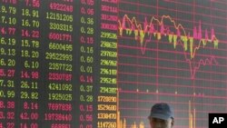 An investor walks past the stock price monitor at a private securities company in Shanghai, China, 21 Oct 2010