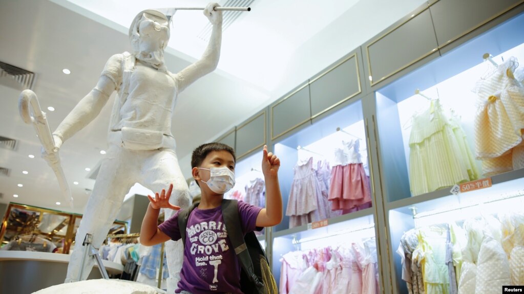 资料照：一名男孩在香港著名童装品牌Chickeeduck的一家门店里树立的“自由女神”像旁摆拍。（2020年6月18日）(photo:VOA)