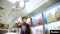 资料照：一名男孩在香港著名童装品牌Chickeeduck的一家门店里树立的“自由女神”像旁摆拍。（2020年6月18日）