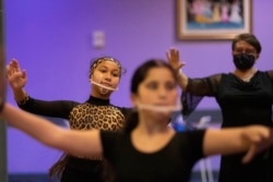 Dancers, wearing face masks to curb the spread of COVID-19 warm up before their lesson at the New Dancing Days school, in Rome, Wednesday, March 24, 2021.