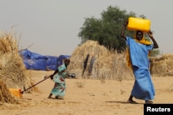 Nigerien displaced people carry water in a camp of the city of Diffa, Niger, June 18, 2016.