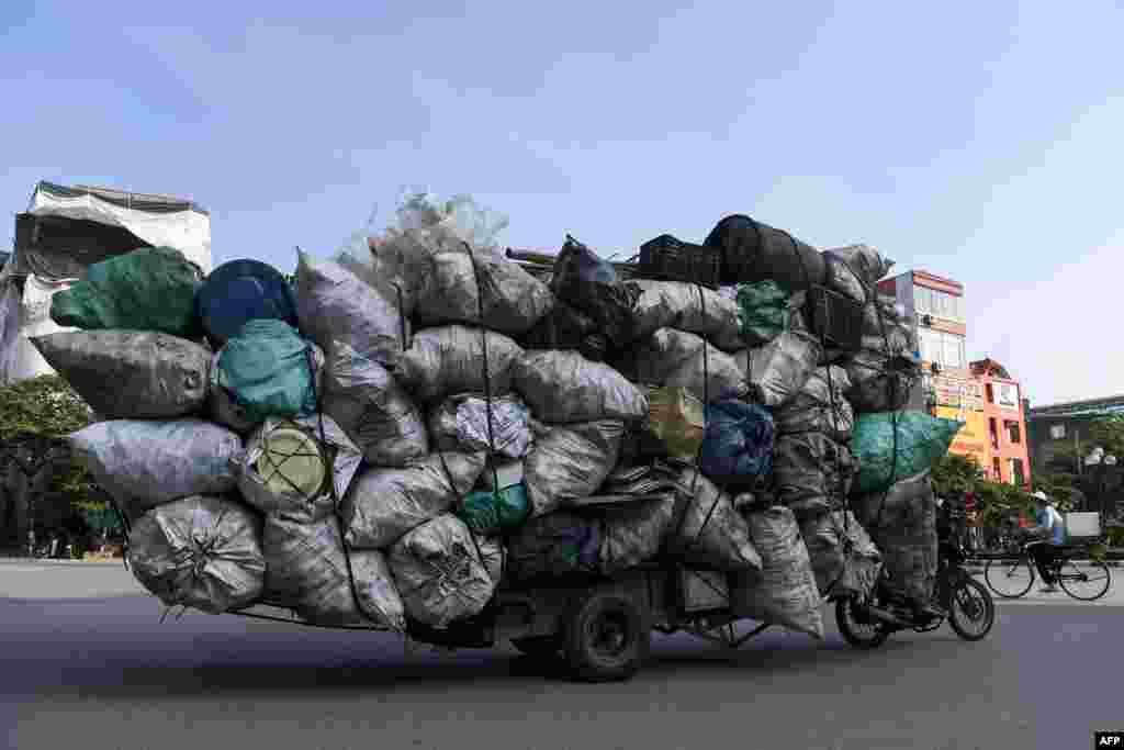 A waste collector on a motorbike transports a large pile of plastic scrap for recycling in Hanoi, Vietnam.