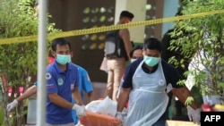 FILE - Paramedics take away a body after four Thai civil defense volunteers were shot and killed outside of a school in the restive southern province of Pattani, Thailand, Jan. 10, 2019.