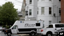 Kendaraan polisi di depan sebuah rumah bertingkat di Everett, Mass., yang digeledah terkait penembakan seorang tersangka oleh polisi di Boston (2/6). (AP/Steven Senne)