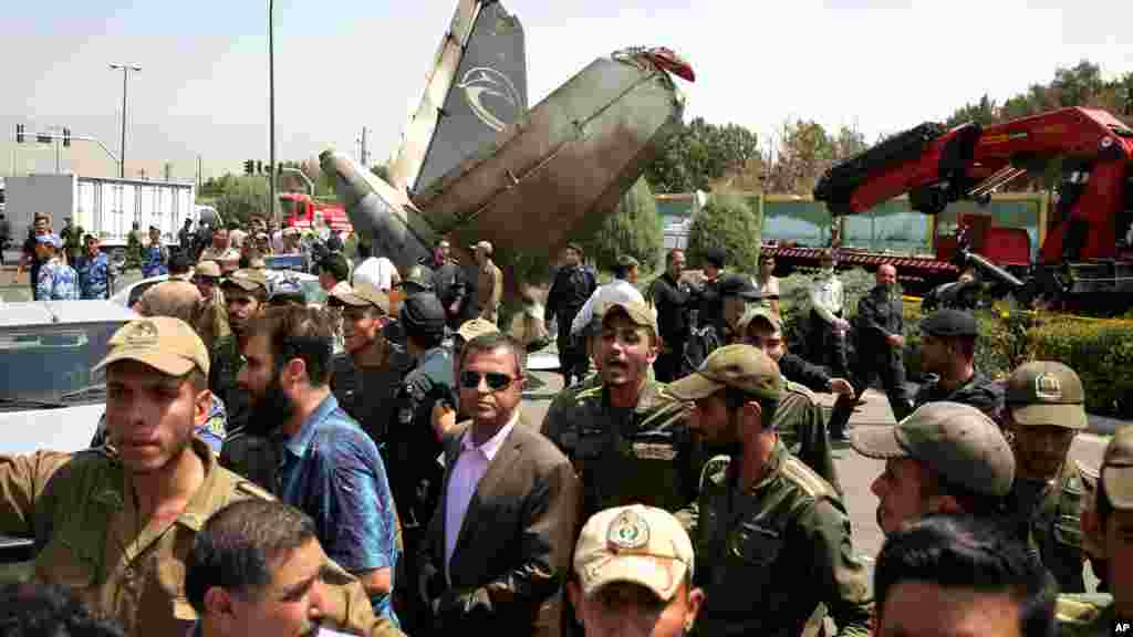 Iranian police and army soldiers direct people and media at the scene of a passenger plane crash near the capital Tehran, Iran, Aug. 10, 2014.