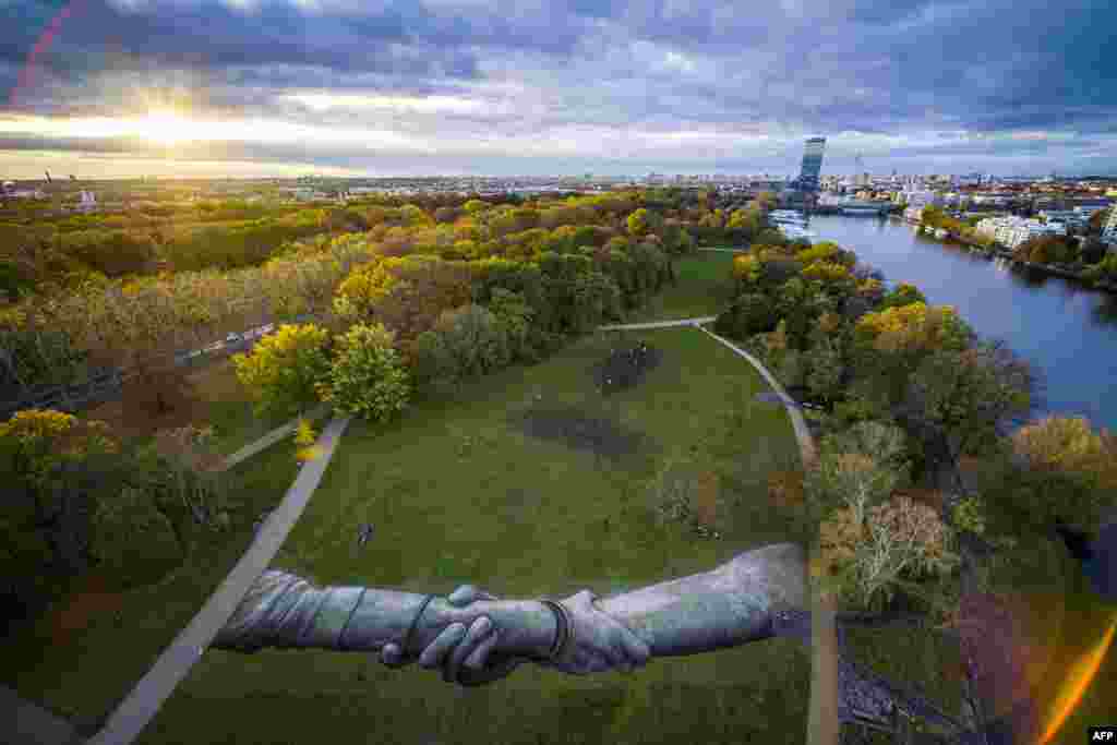 This handout picture released by Saype and Valentin Flauraud shows a giant biodegradable land art painting by French-Swiss artist Saype representing two hands clasped together in the Treptower Park in Berlin, part of his &quot;Beyond Walls&quot; project.