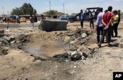 FILE - Civilians inspect a crater caused by a car bombing at an open-air market selling fruit, vegetables and meat in Baghdad's southeast suburb of Nahrawan, Iraq, April 30, 2016. The Islamic State group claimed responsibility for a bombing.