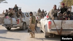 Shi'ite fighters and Iraqi army members ride in vehicles during a patrol in Jurf al-Sakhar, Oct. 25, 2014.